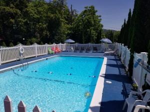 a swimming pool with chairs and a white fence at Seven Dwarfs Cabins - White Cabin in Lake George