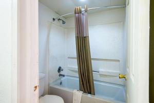 La salle de bains est pourvue d'une douche, de toilettes et d'une baignoire. dans l'établissement Motel 6-Blue Springs, MO, à Blue Springs