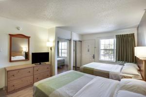 a hotel room with two beds and a television at Studio 6-Stafford, TX - Houston - Sugarland in Stafford