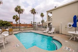 a swimming pool with chairs and a table at Ocean Inn South Padre Island in South Padre Island