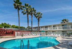 a pool with chairs and palm trees in front of a hotel at Motel 6-Santa Maria, CA - South in Santa Maria