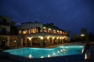 a large house with a swimming pool at night at Naiades Hotel Resort & Conference in Neochori