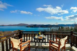 a table and chairs on a balcony with a view of a lake at Naiades Hotel Resort & Conference in Neochori