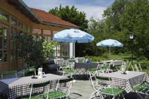 un patio al aire libre con mesas, sillas y sombrillas en Hotel Landgasthof Gschwendtner, en Allershausen