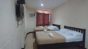 two beds in a small room with a television at Calamba Pension Plaza in Calamba