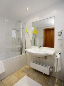 y baño blanco con lavabo y ducha. en Hotel Landgasthof Gschwendtner, en Allershausen