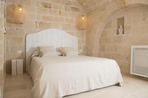 a bedroom with a white bed in a stone wall at Dimora Madina by MANZONI COLLECTION in Monopoli