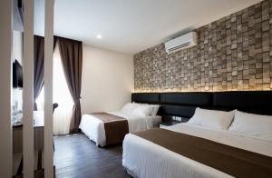 a hotel room with two beds and a brick wall at Gurney Lodge in George Town