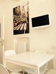 ein weißes Esszimmer mit einem weißen Tisch und einem TV in der Unterkunft Al Centro Città in Bergamo