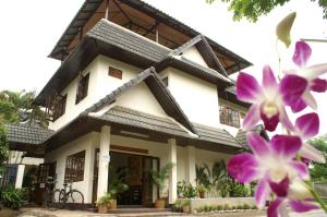 Una casa con flores moradas en el frente. en Trekker Camp, en Chiang Mai
