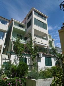 a tall white building with green windows and plants at Apartments Mustapic in Makarska