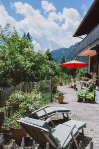 een patio met een tafel en stoelen en een parasol bij Dreimäderlhaus am Berg in Pfronten