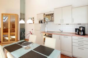 ビンツにあるResidenz Prorer Wiek by Rujanaの白いキャビネット、テーブルと椅子付きのキッチンが備わります。