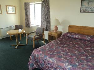 um quarto de hotel com uma cama, uma mesa e cadeiras em Oasis Motel by The Falls em Cataratas do Niágara