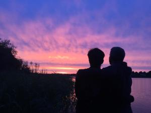 un hombre y una mujer de pie en frente de una puesta de sol en Silkeborg Sø Camping Apartments en Silkeborg