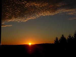 a sunset in a field with the sun in the sky at Pension Thüringer Wald in Reichmannsdorf