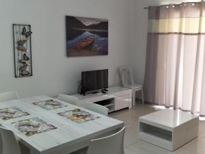 a white dining room with a table and a tv at SunStone Court in St Paul's Bay