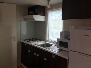 a small kitchen with a sink and a microwave at Camping le Mont Joli Bois in Criel-sur-Mer