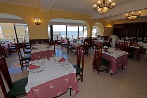 a restaurant with tables and chairs with a view of the ocean at Hotel Restaurante Glasgow in Villadesuso