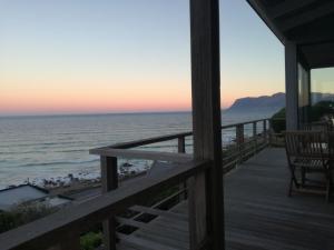 a porch with a view of the ocean at sunset at Seaview Apartment in Muizenberg in Muizenberg