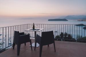 a table and chairs on a balcony with a bottle of wine at Villa Crawford in San Nicola Arcella