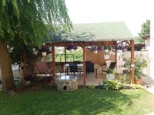 a wooden pergola with a table in a yard at Domboldal Vendégház in Noszvaj