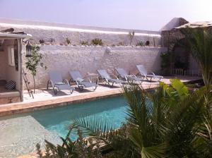 - un groupe de chaises assises à côté de la piscine dans l'établissement Villa Salvatore, à Ghazoua