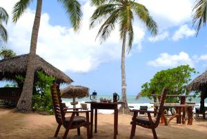 een tafel en stoelen op een strand met palmbomen bij Ibisbird Beach Bungalow in Tangalle