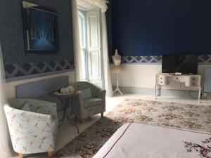 a blue living room with a chair and a tv at Gardenvale Manor House B&B in Stranocum