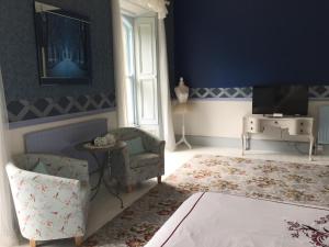 ein blaues Wohnzimmer mit einem Stuhl und einem TV in der Unterkunft Gardenvale Manor House B&B in Stranocum