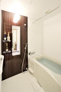 a bathroom with a bath tub and a mirror at Hotel Nets Sapporo in Sapporo