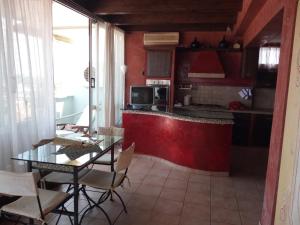 una cucina con pareti rosse, tavolo e sedie di Sky Wellness Apartment a Porto SantʼElpidio