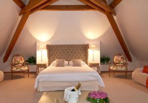 a bedroom with a large bed and two chairs at Les Jardins D'Adalric in Obernai