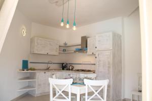 ブドーニにあるTurquoise & Wood Stylish House 23の白いキャビネット、テーブルと椅子付きのキッチンが備わります。