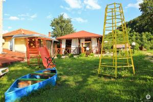 a boat and a ladder in a yard with a house at Guest House Daskalov in Chervena Lokva