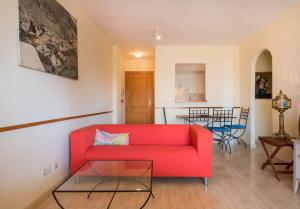 CabopinoにあるSunny beach flatのリビングルーム(赤いソファ、テーブル付)