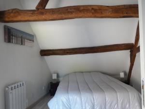 a bedroom with a white bed and wooden beams at Maison De Charme in Cellettes