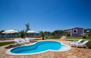 une piscine avec des chaises et des parasols ainsi qu'une maison dans l'établissement Premium Sirena Village Mobile Homes, à Novigrad