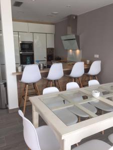 een keuken met een glazen tafel en witte stoelen bij Villa Montgo in L'Escala