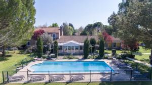 una piscina en un patio con sillas y una casa en Domaine de la Petite Isle - Luberon, en LʼIsle-sur-la-Sorgue