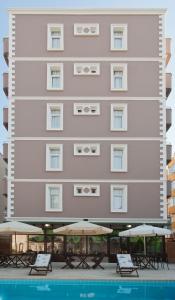 a tall building with tables and umbrellas next to a pool at Triana Hotel in Antalya