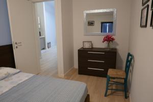 a bedroom with a bed and a dresser and a mirror at Le Querce Apartments in Ronchi