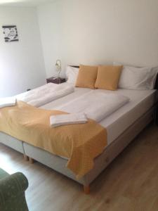 a large bed with white sheets and yellow pillows at Hotel Gloria Budapest City Center in Budapest
