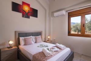 a bedroom with a bed with white sheets and a window at Olive Land Villas in Limenaria
