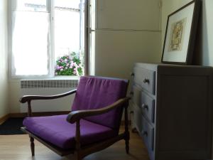 einen lila Stuhl in einem Zimmer mit einer Kommode und einem Fenster in der Unterkunft maison La Marche in Cugand