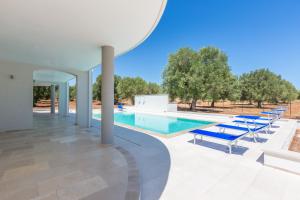 a swimming pool with lounge chairs and a swimming poolvisor at Villa Stella Cadente in Serranova