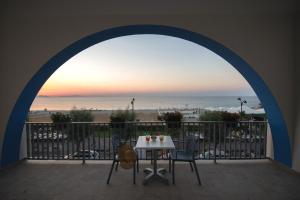 Karma Resort في فينيتيكو: طاولة وكراسي على شرفة مطلة على الشاطئ