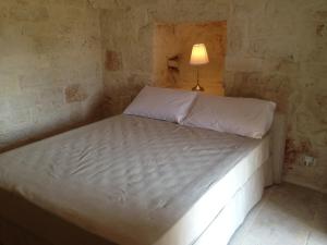 a bed in a room with a lamp on it at Il Granello Di Senape In Valle D'Itria in Locorotondo