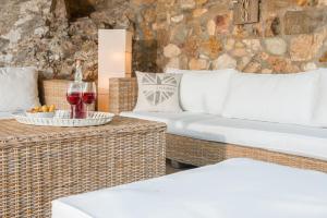 a living room with wicker furniture and a stone wall at Amicasa Private Seaside Suite in Pachis
