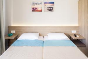 a bedroom with two beds and two tables at Lola's Hotel in Platanias